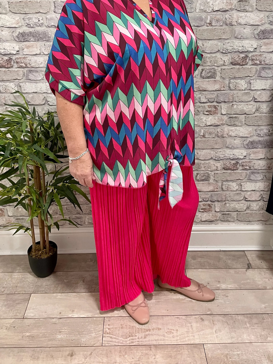 Pleated Palazzo Trouser in bright pink with a colorful geometric top.