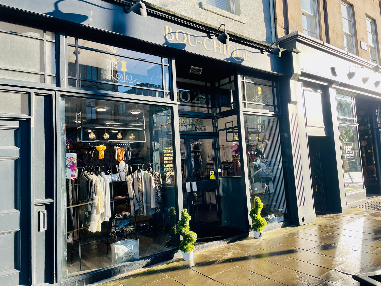 Image of store front with clothing on display taken from the pavement.