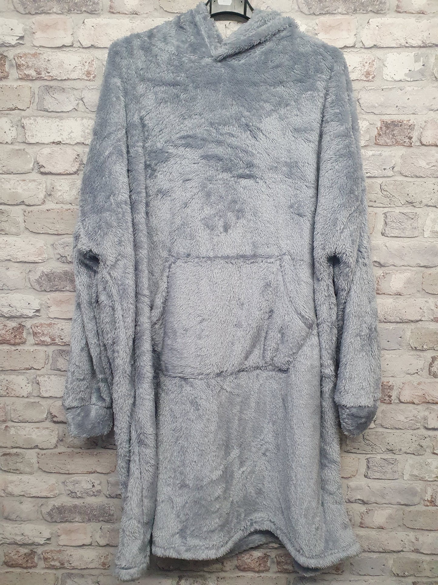Unisex Blanket Hoodie in soft grey with hood and front pocket, made of 100% polyester.