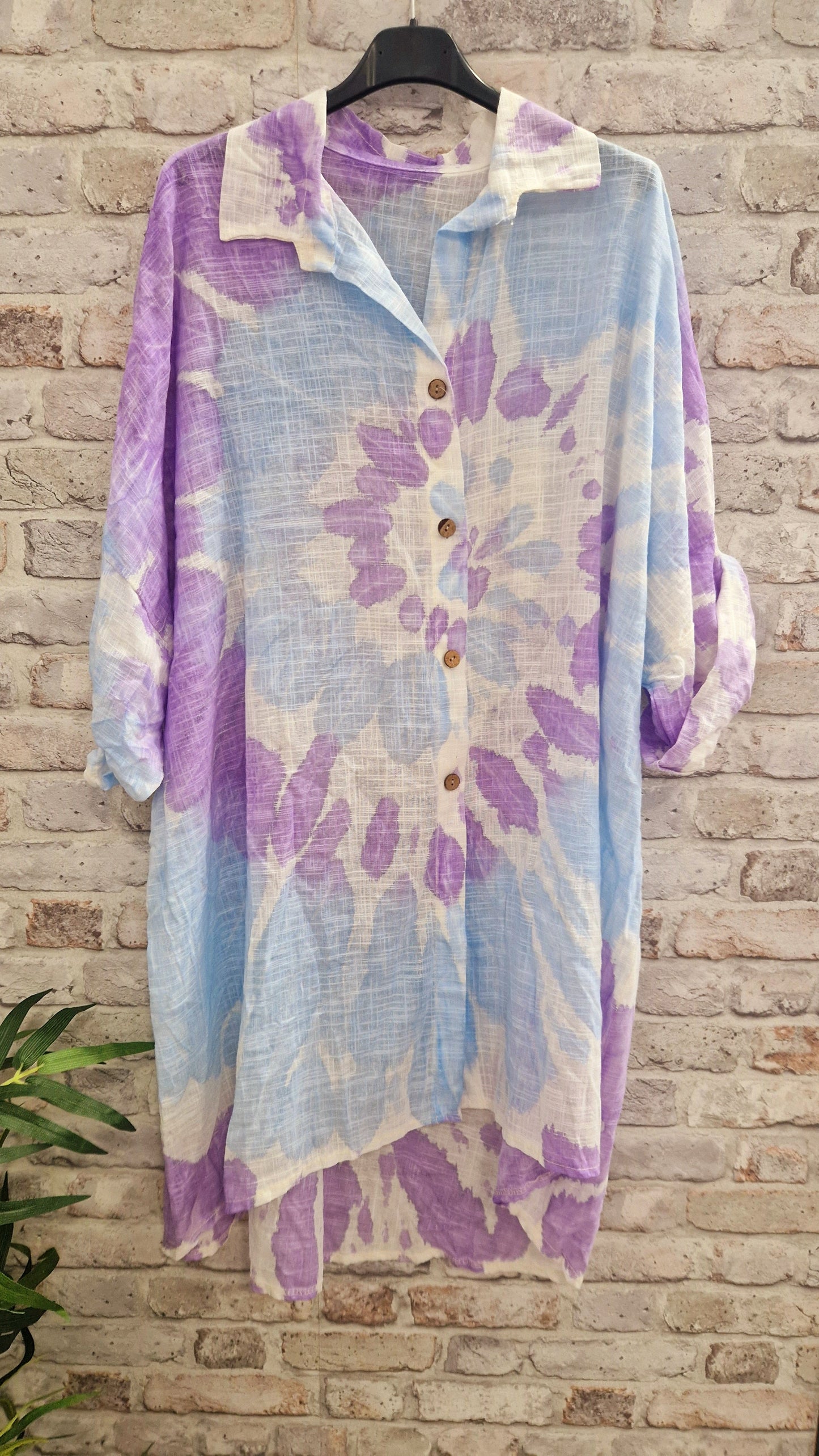 Tie Dye Cotton Shirt with pastel purple and blue pattern hanging on brick wall.