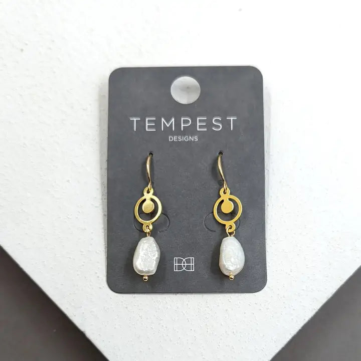 Gold circle and pearl earrings on display card.