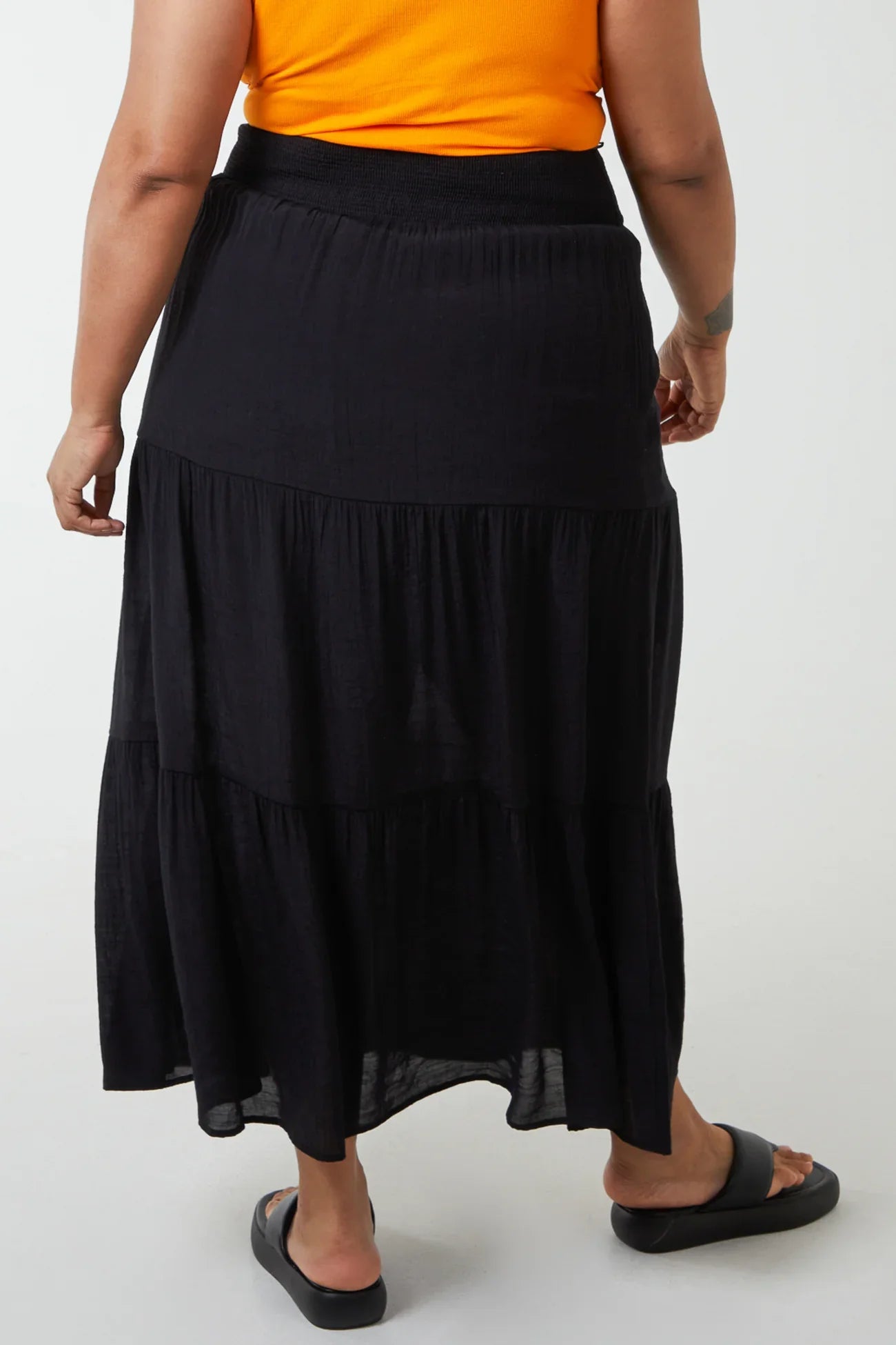 Plus size woman wearing black shirred waist maxi skirt.