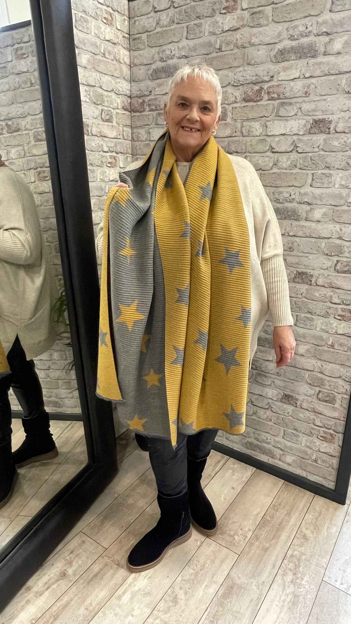Pleated Star Scarf with textured folds and reversible colors, 100% polyester.