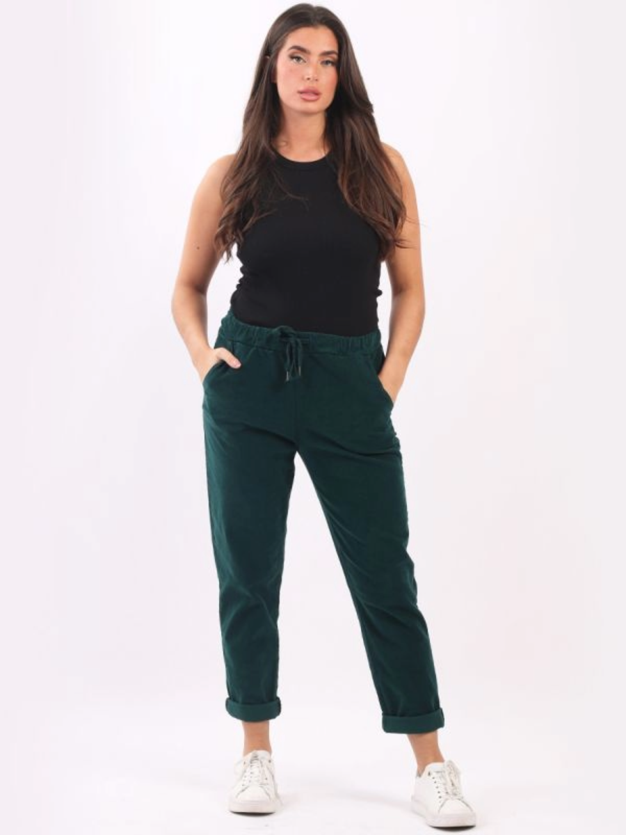 Woman wearing green cotton corduroy trousers with elastic waistband and drawstring.