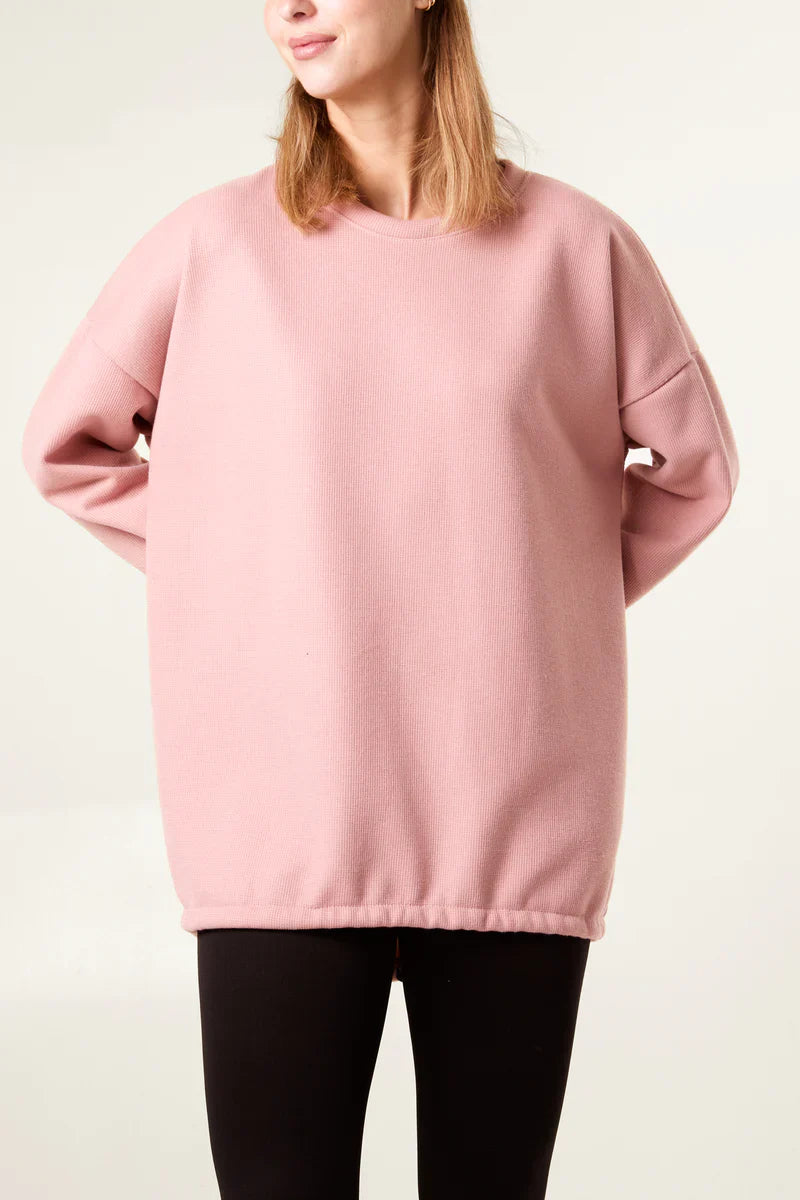 Elastic drawstring back sweatshirt in light pink with soft fleece lining.