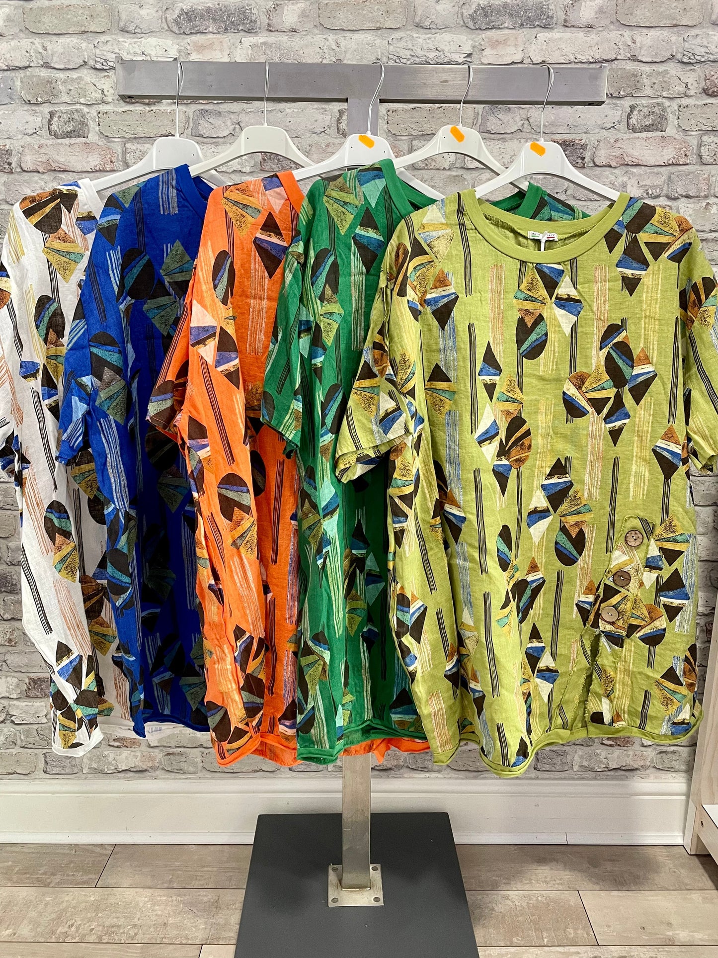 Lagenlook Linen Diamond Slit Tunic in various colors hanging on a rack.