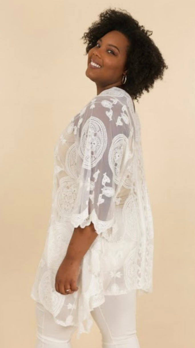 Plus-size model wearing a white lace poncho made of 65% cotton and 35% nylon.