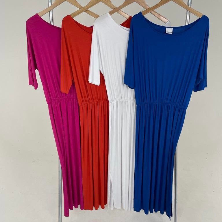 Four plain T-shirt dresses in pink, red, white, and blue displayed on hangers.