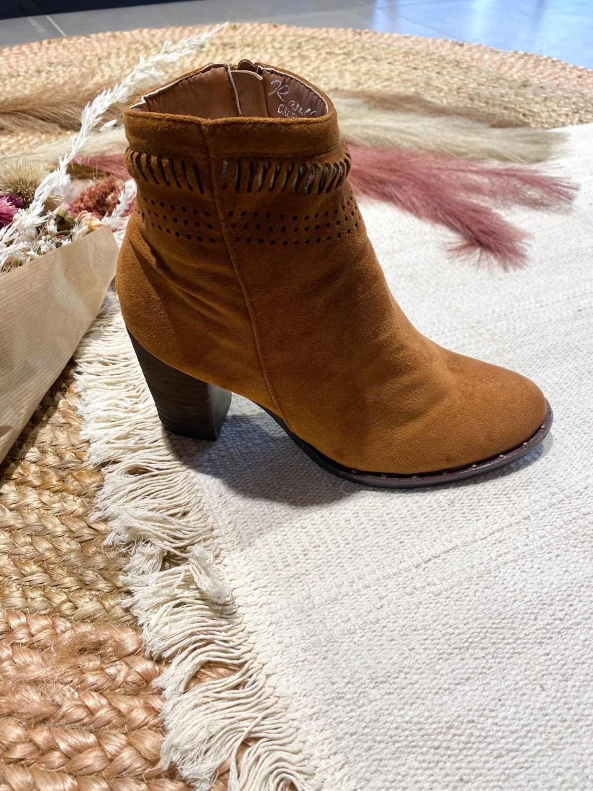 Mid heel boot with cut out design on a textured background.
