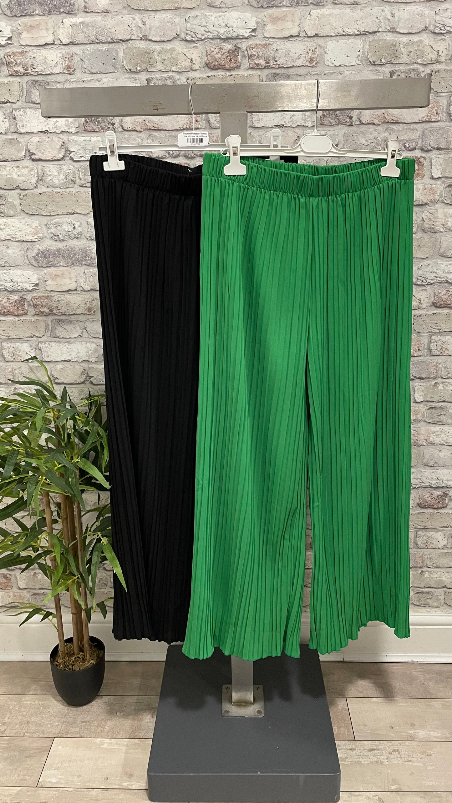 Pleated Palazzo Trouser in black and green fabric hanging on a rack.