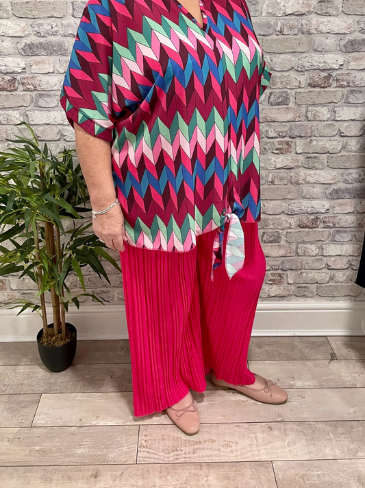 Pleated Palazzo Trouser in bright pink with a colorful geometric top.
