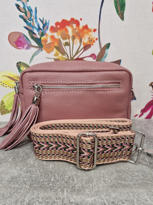 Pink leather bag with matching strap and floral background.