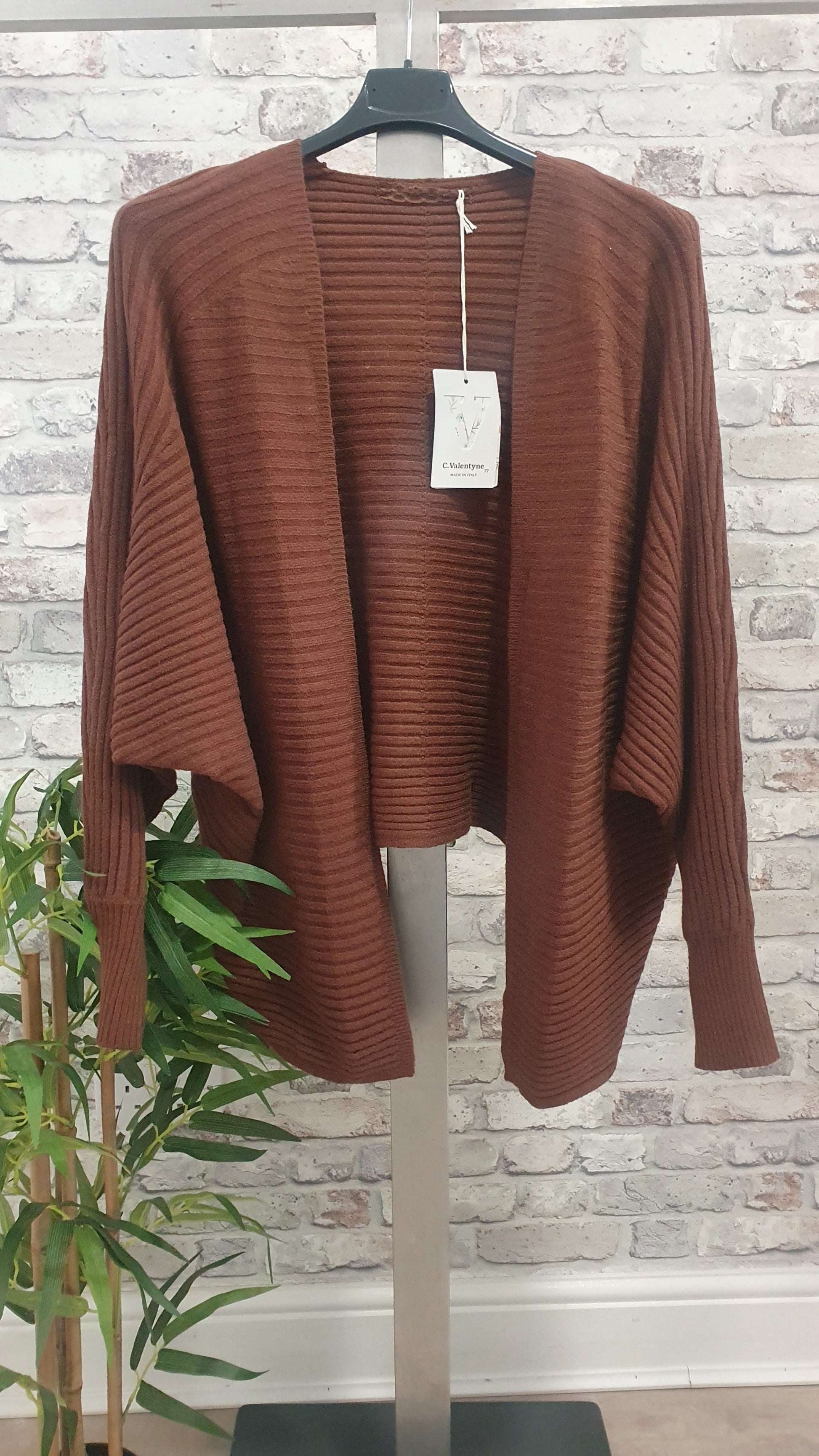Ribbed Batwing Cardigan with open front and batwing sleeves on hanger against textured wall.
