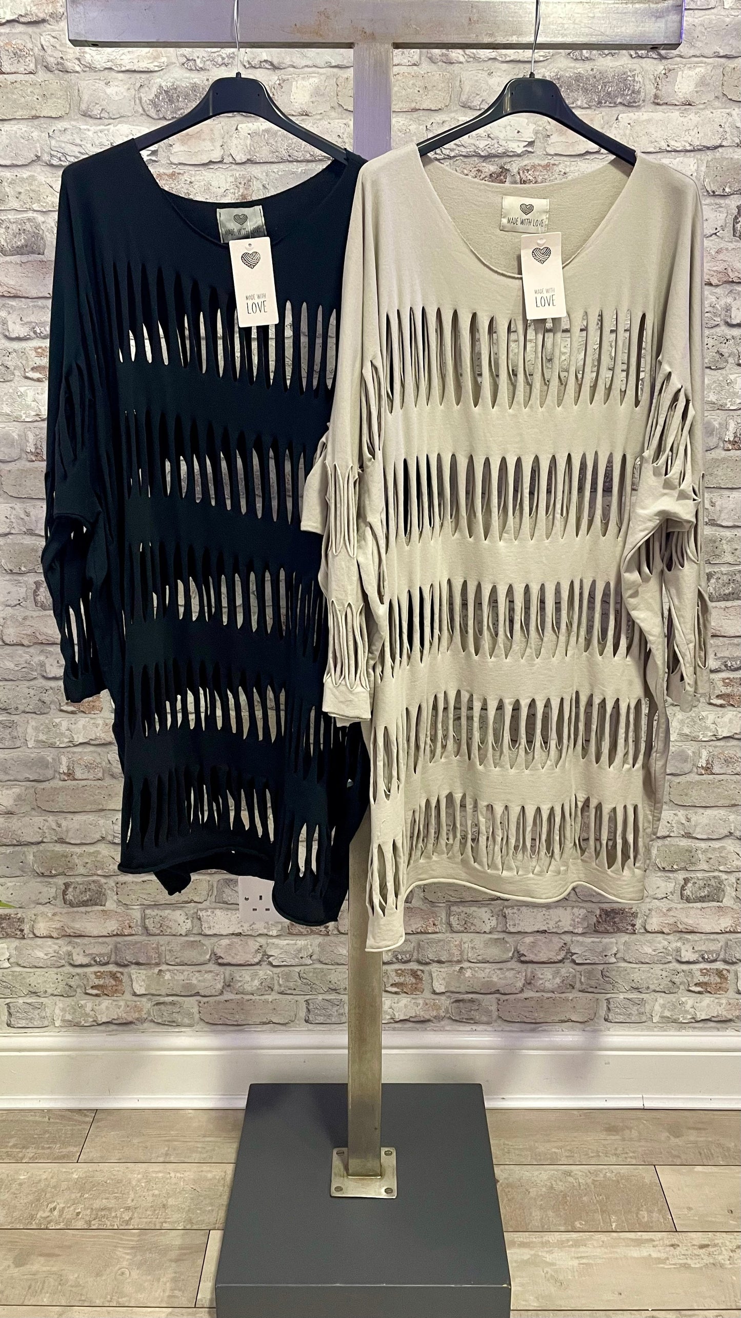 Perforated Layering Tunic in black and beige hanging on display.